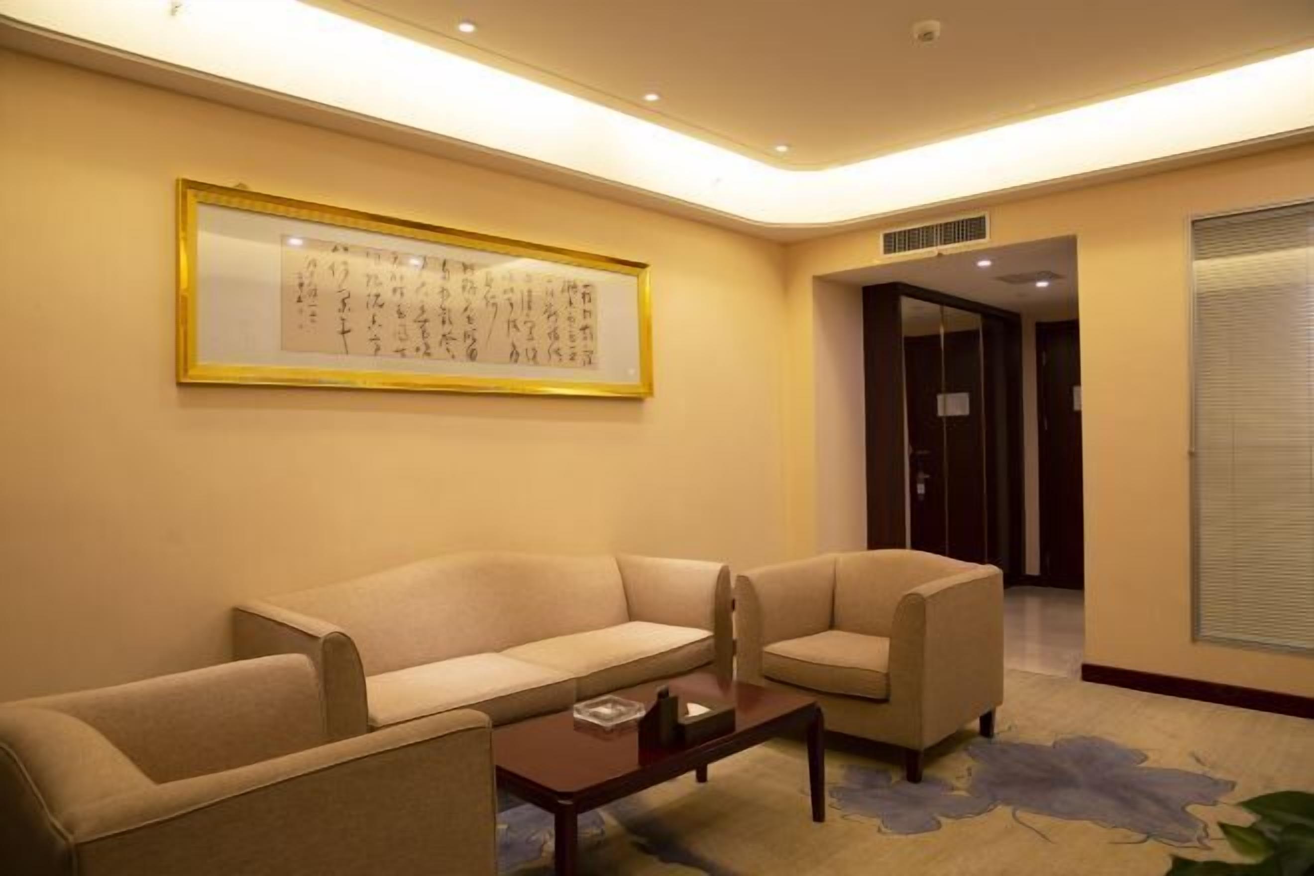 A hotel lobby with a beige sofa, a small table, and a framed calligraphy piece on the wall.