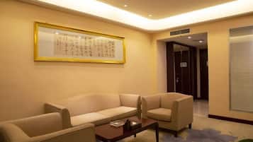 A hotel lobby with a beige sofa, a small table, and a framed calligraphy piece on the wall.