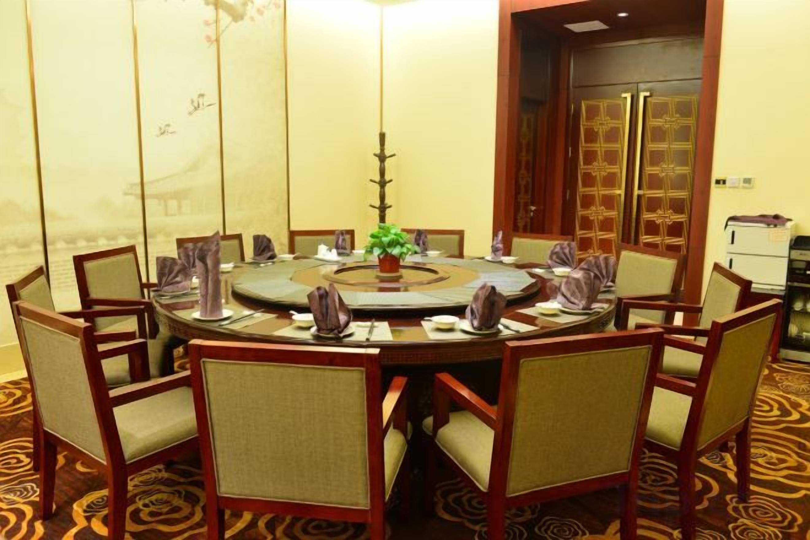 Une table de salle à manger ronde, avec des chaises, une plante au centre et un élément décoratif en guise de centre de table.