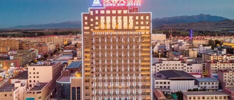 A multi-story hotel with a prominent sign at the top, surrounded by other buildings.
