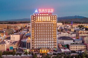 A multi-story hotel with a prominent sign at the top, surrounded by other buildings. - Min Le Long Xin Hotel (Minle)