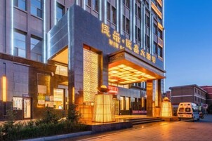 Una entrada de hotel moderna con señalización iluminada y un área de acceso cubierta.