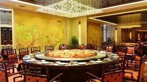A round dining table with chairs, a chandelier, and a mural on the wall. - Min Le Long Xin Hotel (Minle)