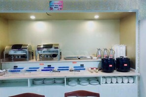 Montaje de bufé con estaciones de comida autoservicio, dispensadores de condimentos y una variedad de recipientes y platos.