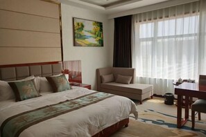 A hotel room with a large bed, a desk, a chair, a painting on the wall, and a window with curtains. - Yunshan Hotel (Jishishan)