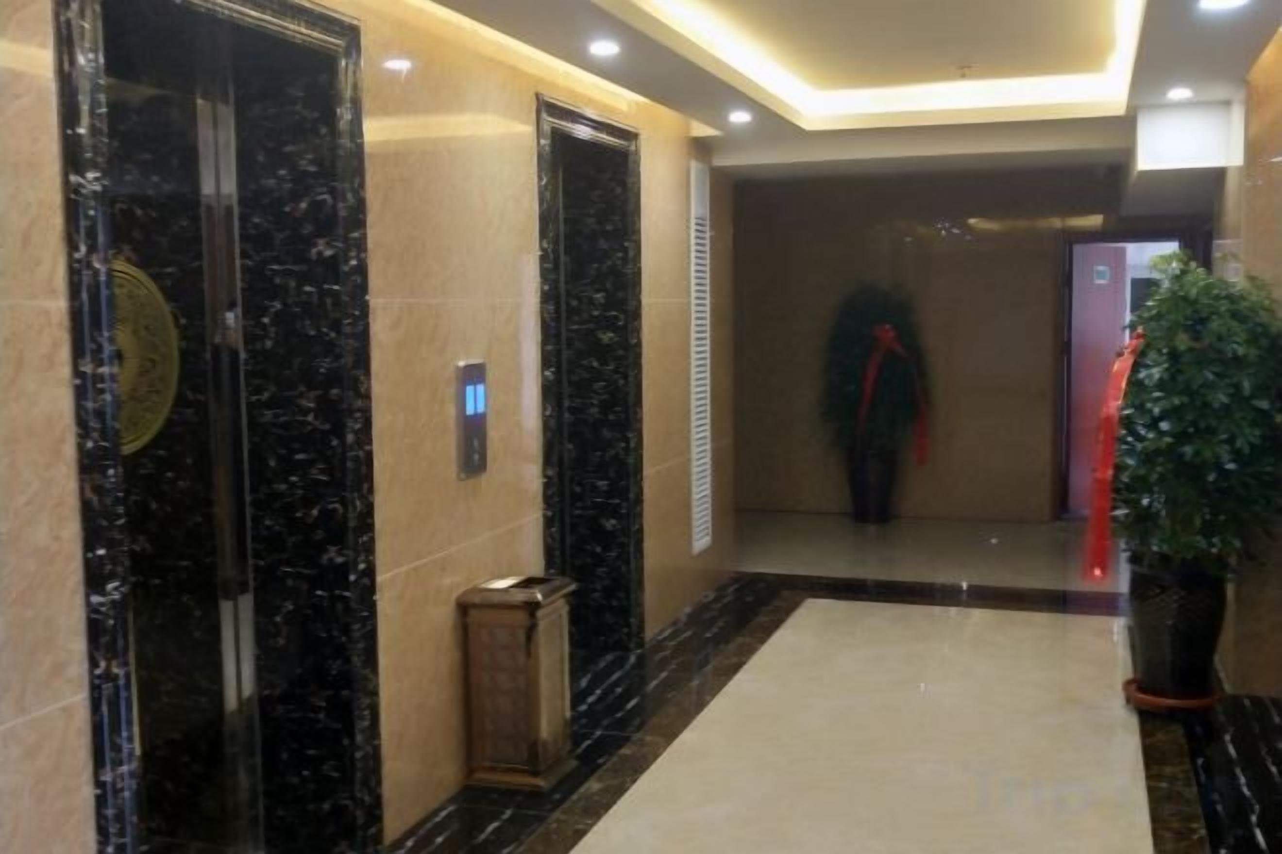 A hallway with marble flooring, a potted plant, and a red object on the right.