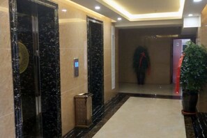A hallway with marble flooring, a potted plant, and a red object on the right. - Yunshan Hotel (Jishishan)