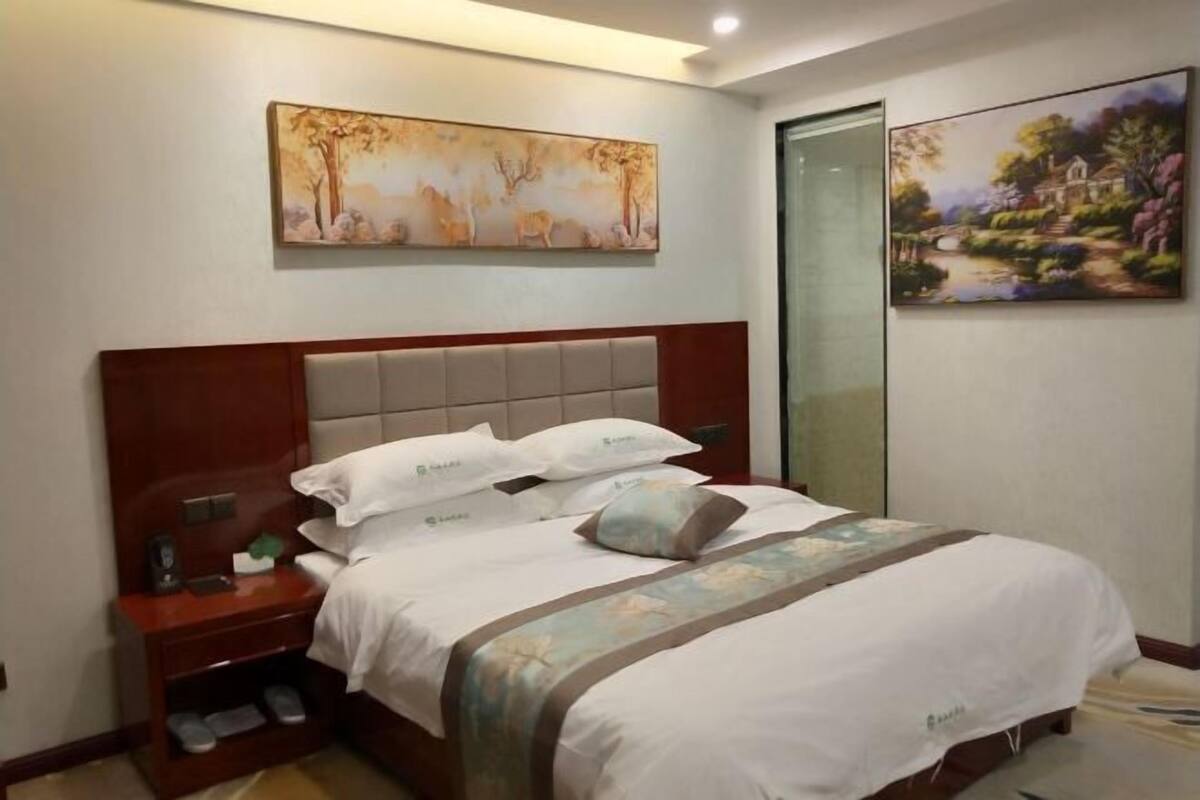 Una habitación de hotel con cama, mesita de noche y un cuadro sobre la cama.
