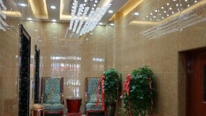 A lobby with marble walls, a red carpet, two potted plants, and a chandelier. - Yunshan Hotel (Jishishan)