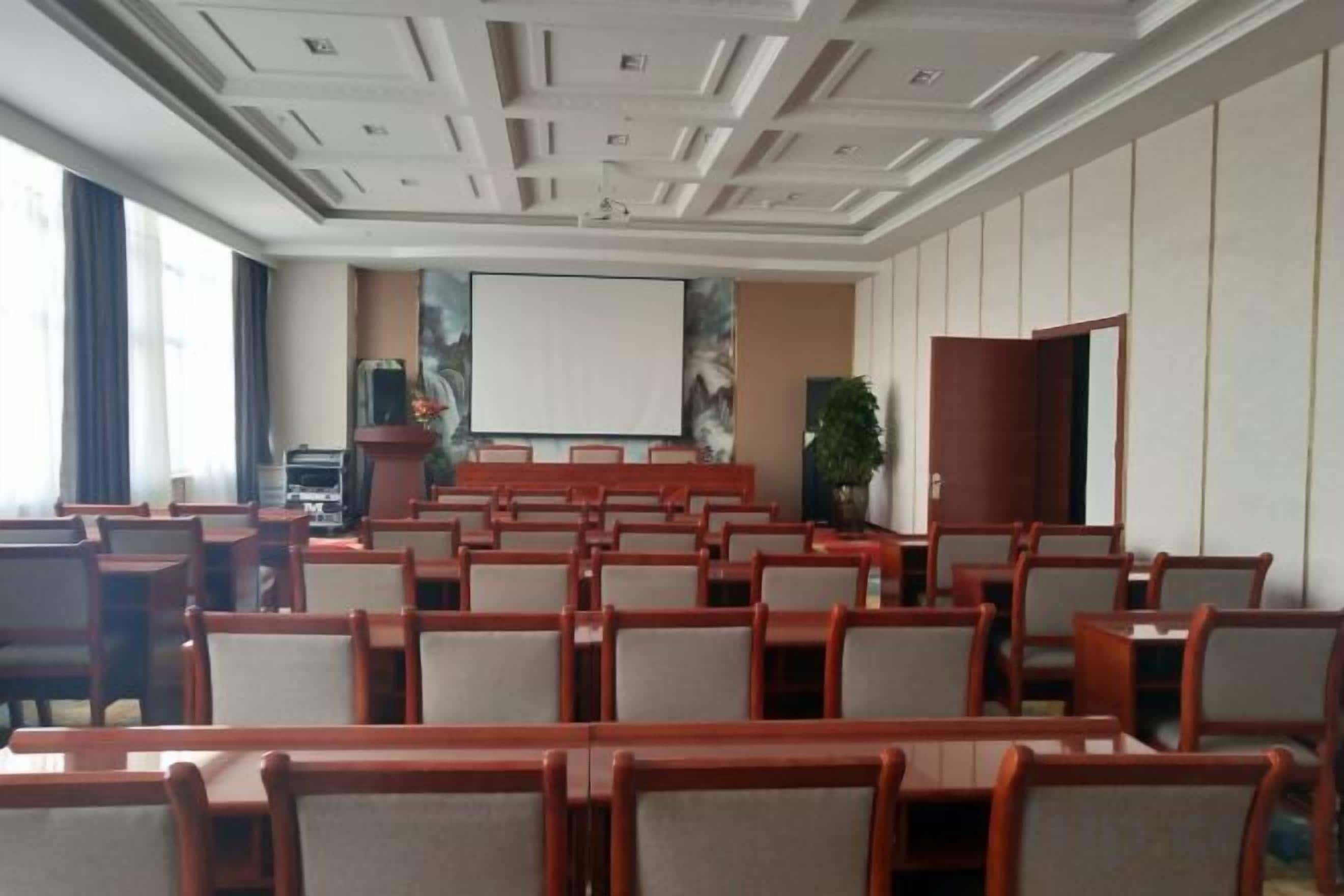 A conference room with rows of chairs, a projector screen, and a podium.