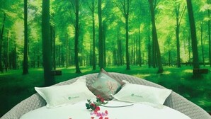 A bed with white linens and two pillows, set against a forest backdrop. - Yunshan Hotel (Jishishan)