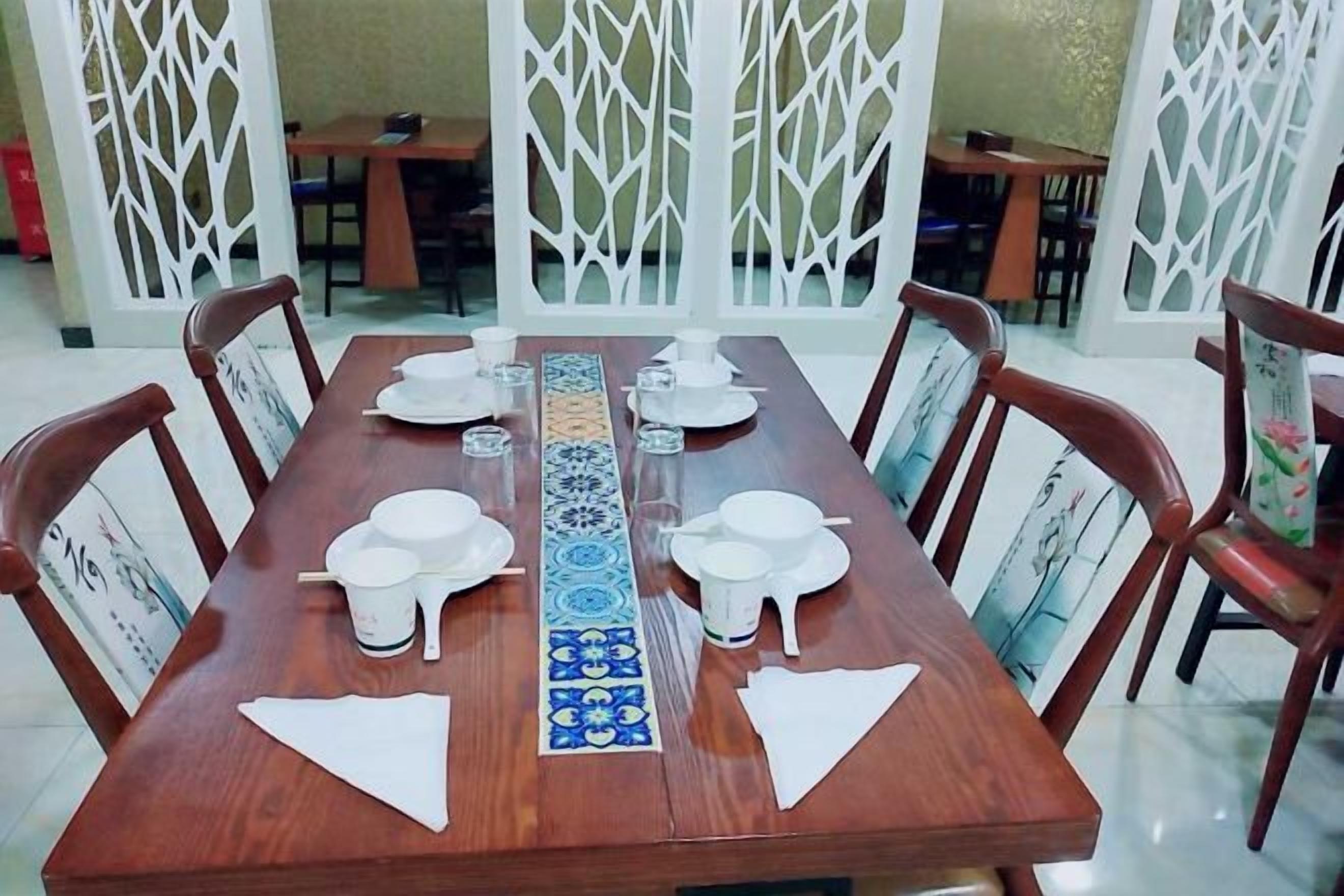 A dining table set with white plates, bowls, and a decorative tray.