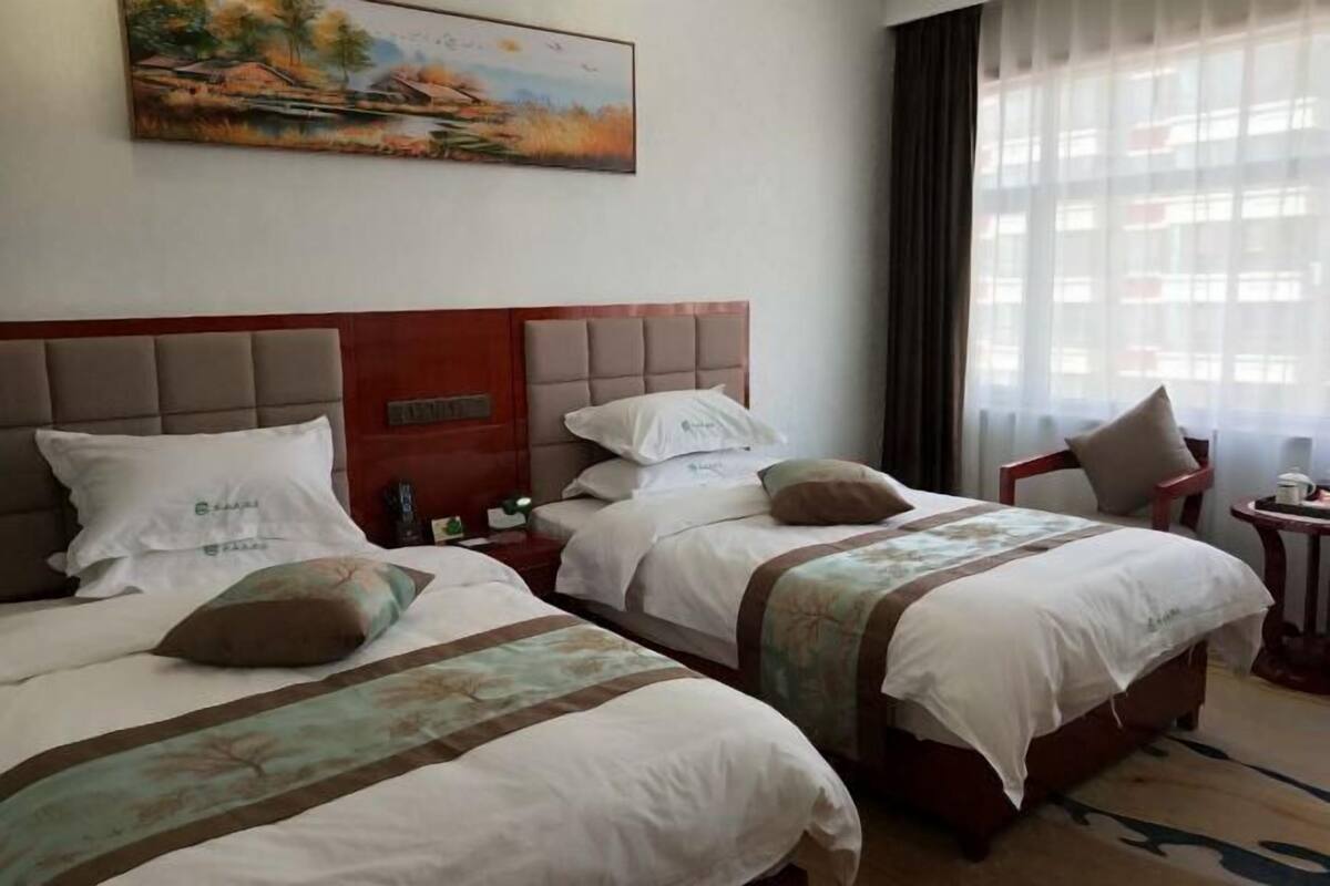Habitación de hotel con dos camas, un cuadro en la pared y una ventana con cortinas.