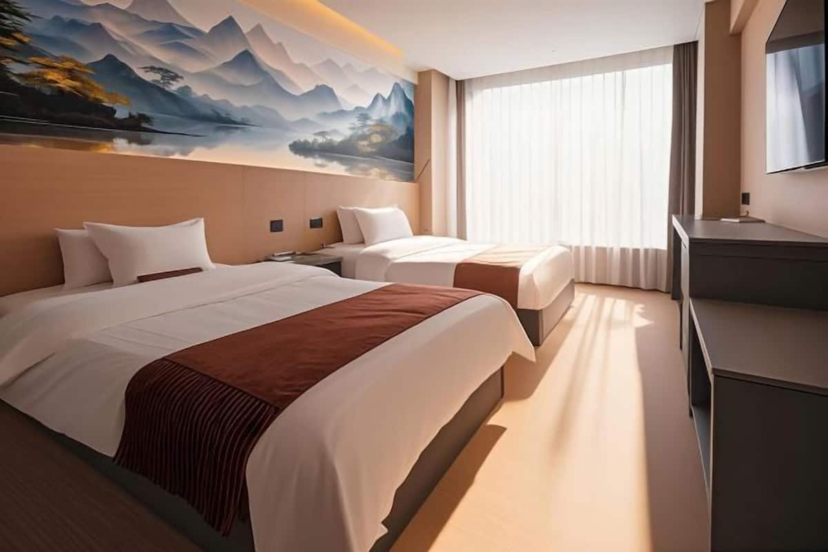 Habitación de hotel con dos camas, un cuadro grande en la pared, un televisor y un escritorio.