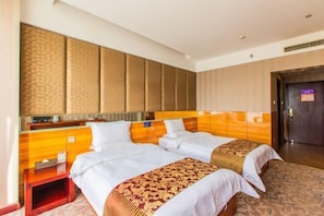 A hotel room with two beds, a wooden headboard, a small bedside table, and a wardrobe.