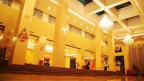 A spacious lobby with high ceilings, chandeliers, and a staircase leading to upper levels. - Tian Yi Hotel (Zuoquan)