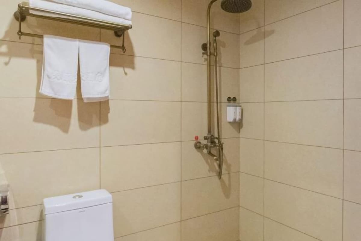 A bathroom with a shower, a toilet, and a towel rack with two towels.
