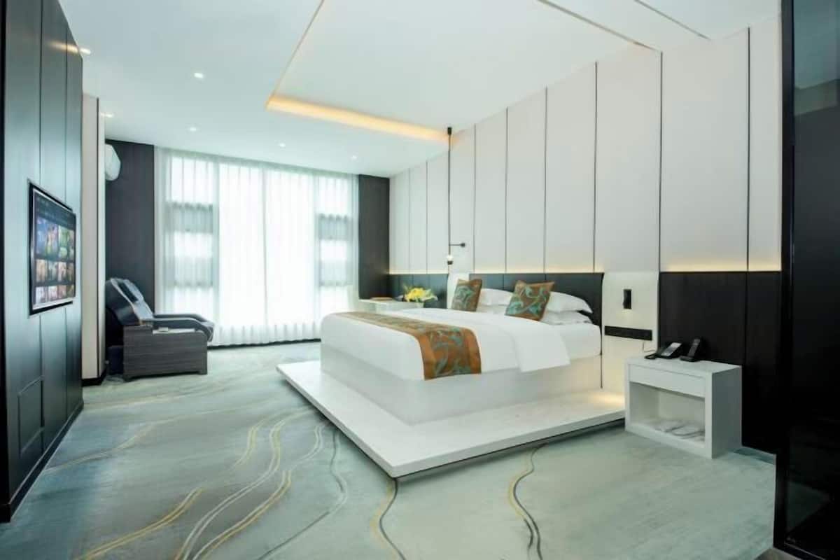 A modern hotel room with a large bed, a desk, and a chair.