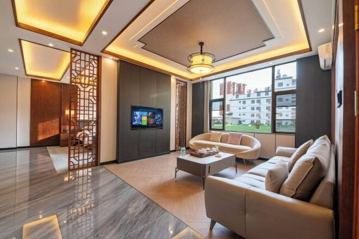 A modern living room with a sofa, coffee table, TV, and a decorative screen.