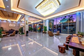 Un vestíbul d'hotel modern amb un penjador de cristall, zones d'estar i una recepció.