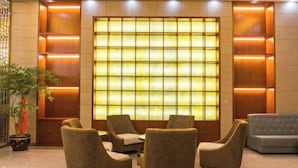 Un hall d’entrée doté d’un grand mur illuminé, de plusieurs canapés et d’une plante en pot.