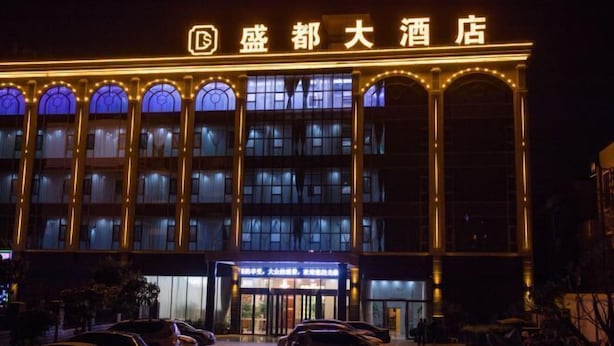 Un hôtel avec une enseigne bien visible, écrite en caractères chinois, de nombreuses fenêtres et une entrée bien éclairée.