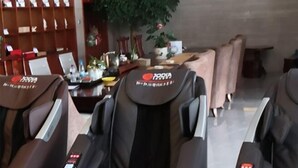 Un espace détente avec des fauteuils massants de la marque « KARMA » et une bibliothèque en arrière-plan.