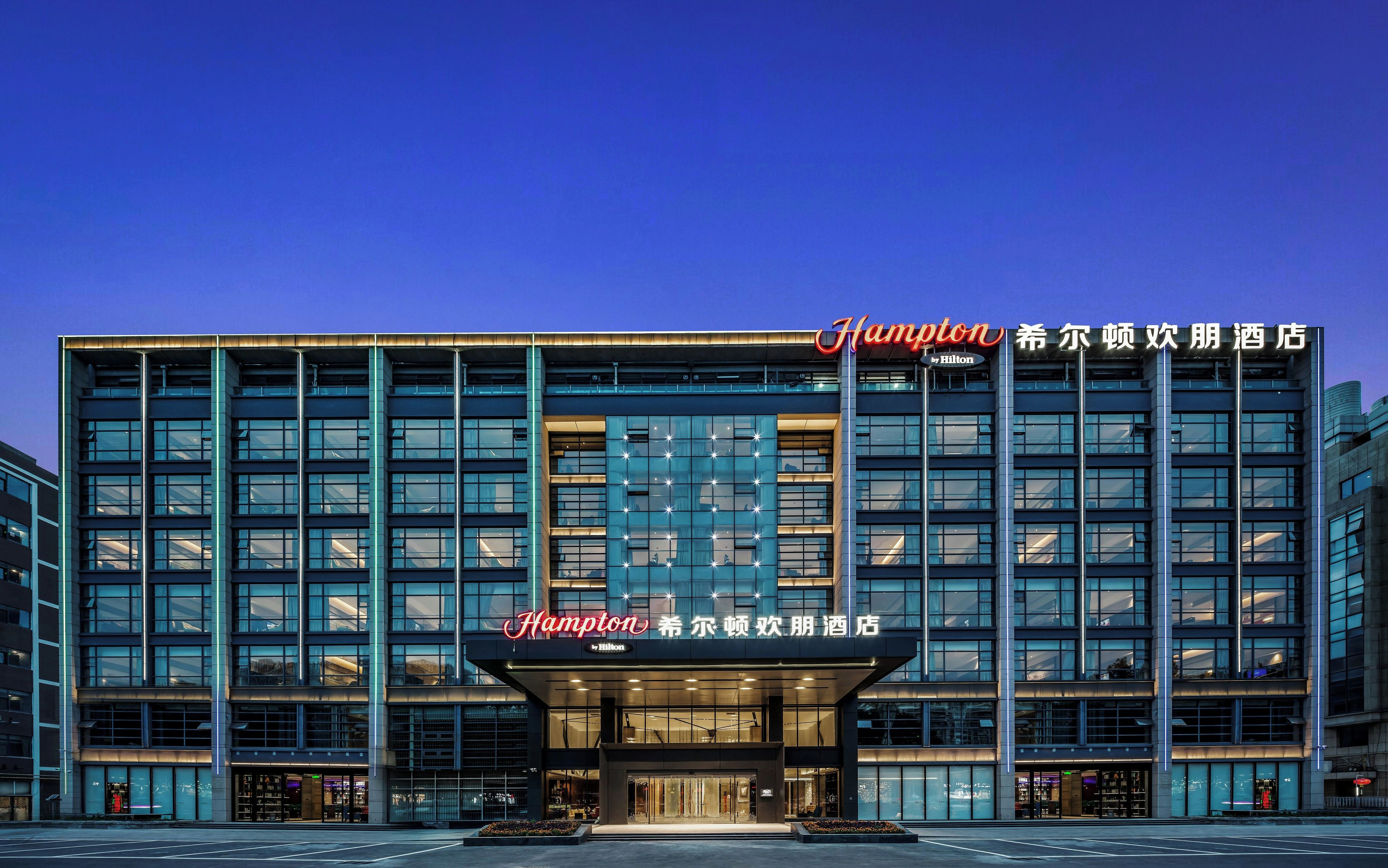 Un hôtel moderne, reconnaissable à son grand panneau « Champion », à ses larges fenêtres et à son entrée bien éclairée.
