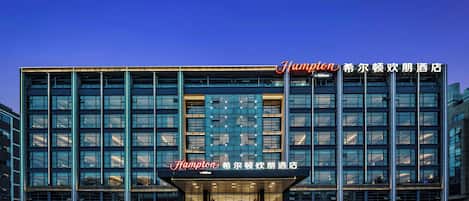 Un hôtel moderne, reconnaissable à son grand panneau « Champion », à ses larges fenêtres et à son entrée bien éclairée.