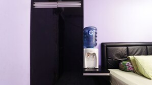 A room with a black wardrobe, a water dispenser, and a bed with a green pillow. - Dinda Apartemen Tangerang by Zuzu (Tangerang)