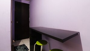 A narrow hallway with a purple wall, a black door, a small stool, and a black shelf. - Dinda Apartemen Tangerang by Zuzu (Tangerang)