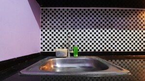 A kitchen with a checkered backsplash, a stainless steel sink, and a black countertop. - Dinda Apartemen Tangerang by Zuzu (Tangerang)
