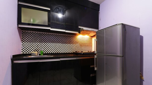 A compact kitchen with black cabinets, a stainless steel refrigerator, and a checkered backsplash. - Dinda Apartemen Tangerang by Zuzu (Tangerang)