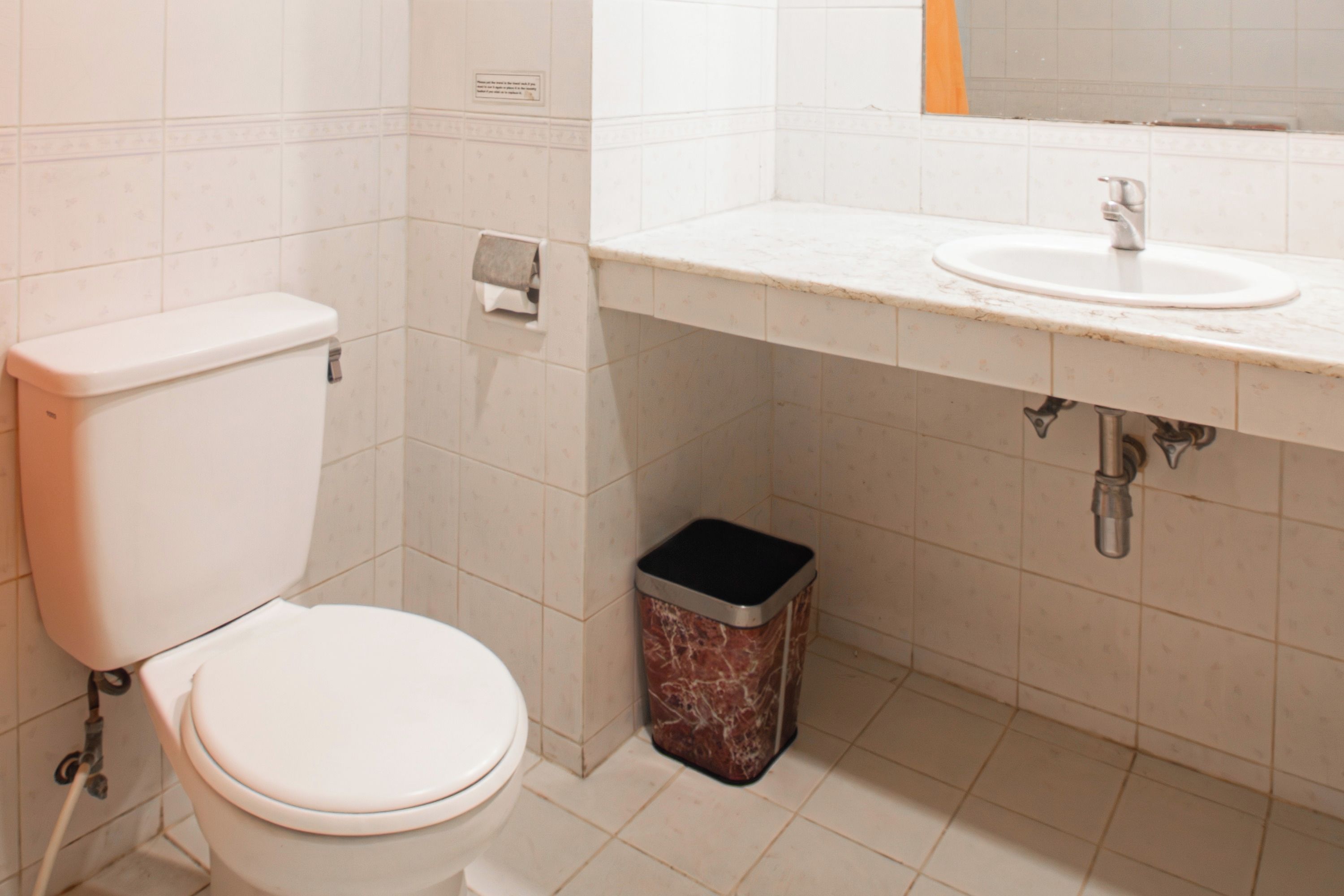 A bathroom with a toilet, sink, and trash bin.