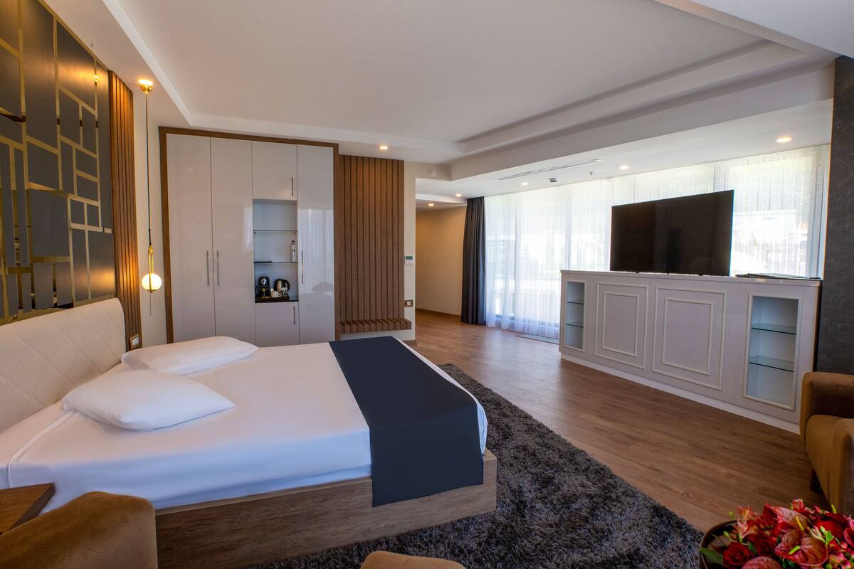 Habitación de hotel moderna con una cama grande, televisión de pantalla plana, zona de estar y kitchenette.