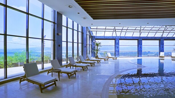 A modern indoor pool area with large windows offering views of a mountainous landscape. - Cabir Deluxe Hotel (Sapanca)