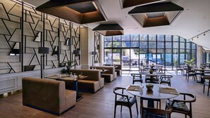 A modern hotel lobby with a geometric wall design, comfortable seating, and large windows offering a view of the outdoors. - Cabir Deluxe Hotel (Sapanca)