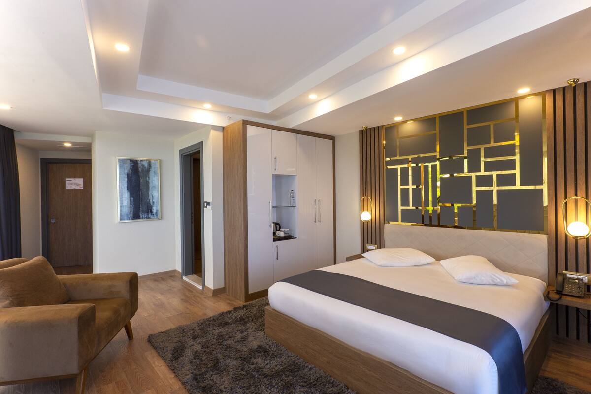 Una habitación de hotel moderna con una cama grande, un sofá, un escritorio y un teléfono en la pared.