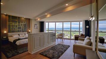 A modern bedroom with a large bed, a desk, and a view of the city.