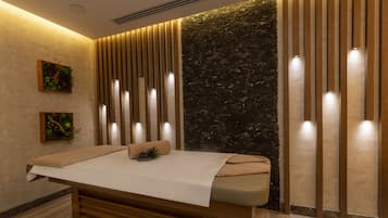 Relax in a serene spa room with a massage table, framed artworks, and a calming atmosphere.