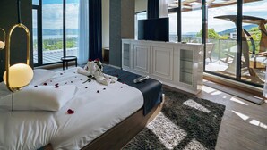 A modern bedroom with a large bed, a television, and a balcony with a view of the landscape. - Cabir Deluxe Hotel (Sapanca)