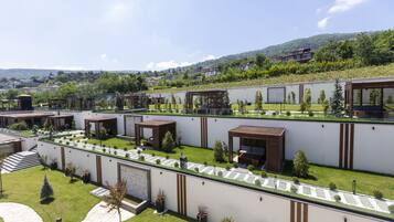 Un edificio moderno con varias habitaciones, un patio central y vistas a un paisaje montañoso.