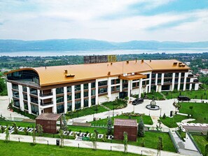 A modern building with a curved roof, large windows, and a landscaped courtyard. - Cabir Deluxe Hotel (Sapanca)