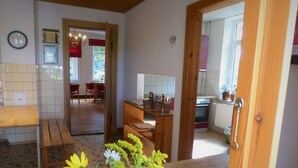 Une cuisine avec des meubles de rangement en bois, un évier et une cuisinière. On y trouve également un coin repas avec une table et des chaises.