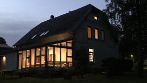 Une maison moderne dotée de grandes fenêtres, d’un toit en pente et d’un intérieur bien éclairé.