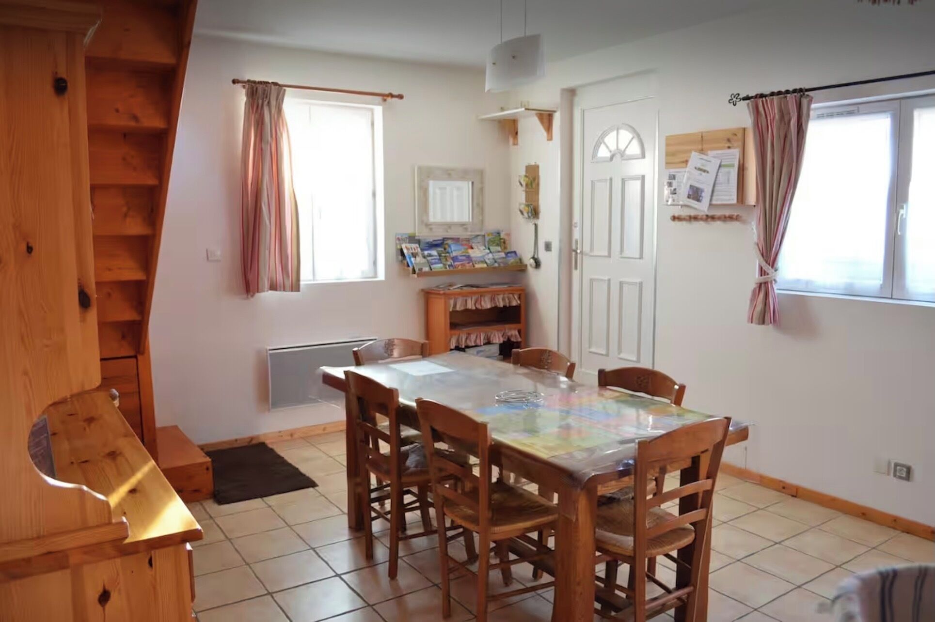 Un coin repas avec une table et des chaises en bois, une bibliothèque intégrée et une fenêtre avec des rideaux.