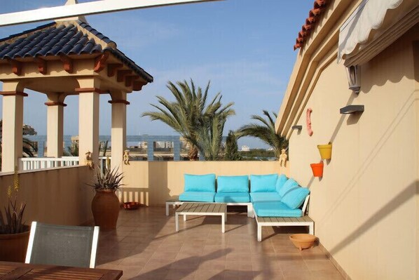 A terrace with a white sofa set, a wooden table, and a decorative gazebo.