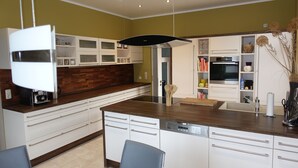 Une cuisine moderne avec des meubles blancs, un îlot central et un four encastré.
