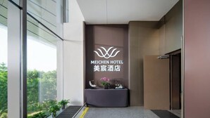 A reception area with a logo for Meichen Hotel, a reception desk, and a view of greenery outside. - MeiChen Hotel( within the terminal building of Beijing Daxing International Airport) (Beijing)