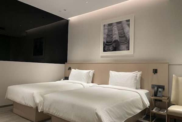 A modern hotel room with two beds, a large artwork on the wall, and a bedside table with a phone. - MeiChen Hotel( within the terminal building of Beijing Daxing International Airport) (Beijing)